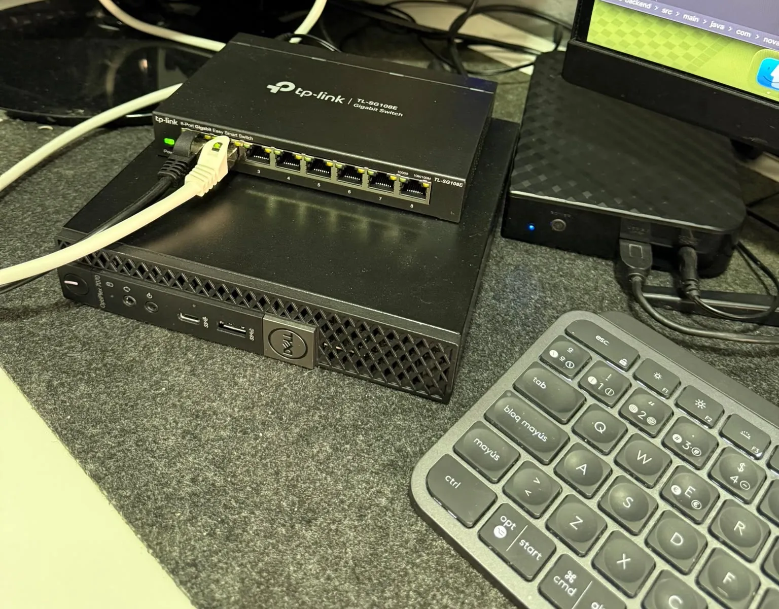 The Dell OptiPlex 7070 Micro on the desk with the TP-Link TL-SG108E switch on top, the 6 TB Verbatim drive to the right and a keyboard in front